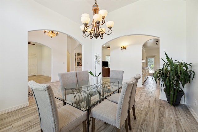 dining area with light wood-type flooring and an inviting chandelier