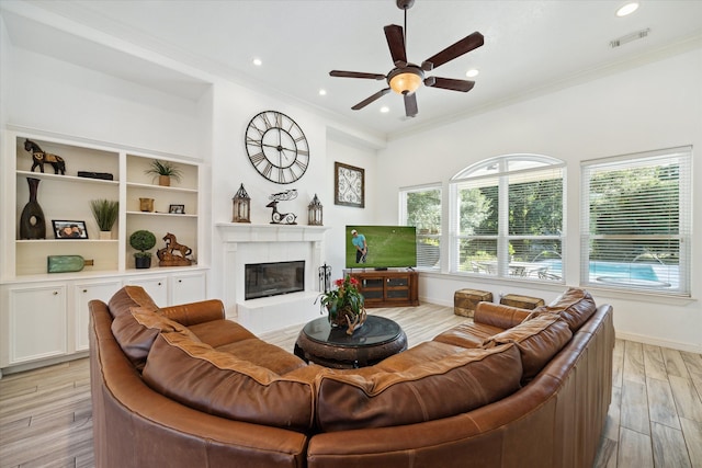 living room with ceiling fan, light hardwood / wood-style floors, crown molding, and a fireplace