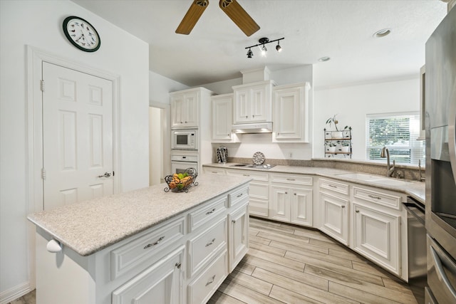 kitchen featuring a center island, white cabinets, sink, light wood-type flooring, and stainless steel appliances