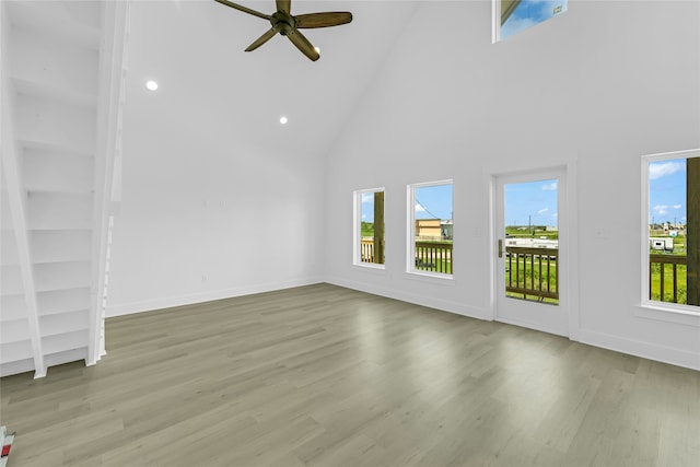 unfurnished living room with light wood-type flooring, high vaulted ceiling, and a healthy amount of sunlight