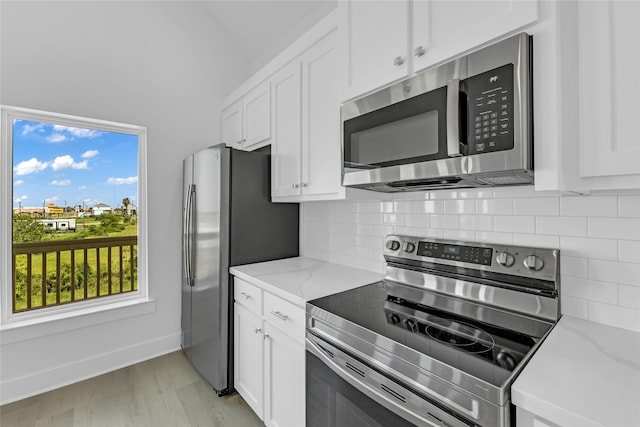 kitchen with stainless steel appliances, light hardwood / wood-style floors, decorative backsplash, light stone countertops, and white cabinets