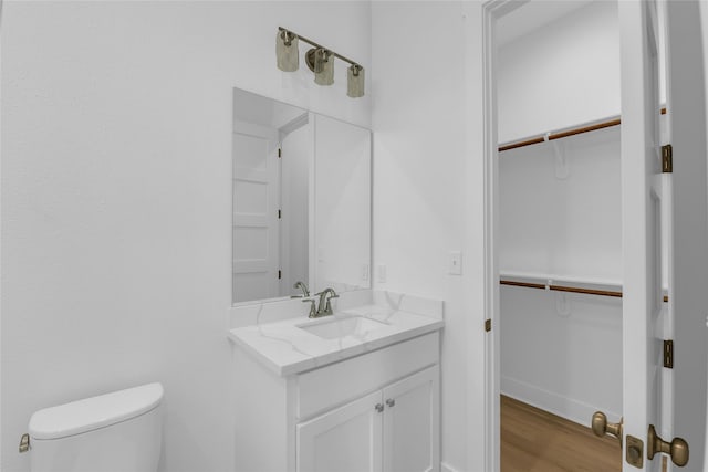 bathroom with baseboards, vanity, toilet, and wood finished floors