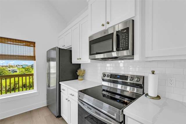 975 Alberdie Dr, Crystal Beach, TX 77650 - kitchen with appliances with stainless steel finishes, decorative backsplash, white cabinets, lofted ceiling, and light wood finished floors