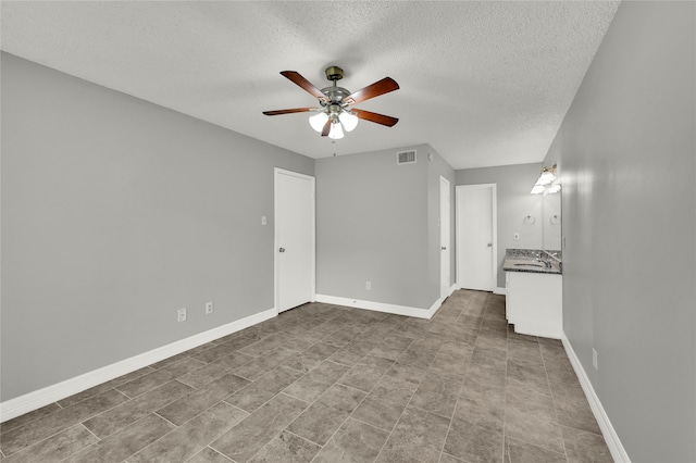 unfurnished room with ceiling fan, a textured ceiling, sink, and tile patterned floors