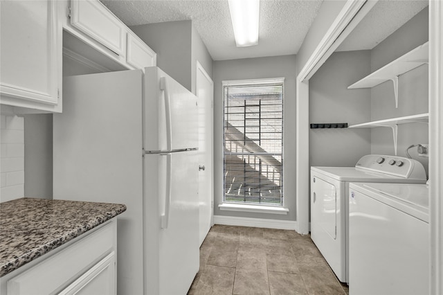 washroom with a textured ceiling, washer and clothes dryer, and light tile patterned floors