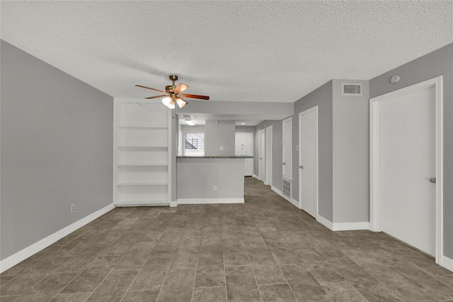 unfurnished living room featuring ceiling fan, tile patterned flooring, a textured ceiling, and built in features