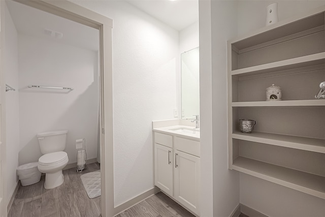 bathroom with toilet, vanity, and wood-type flooring