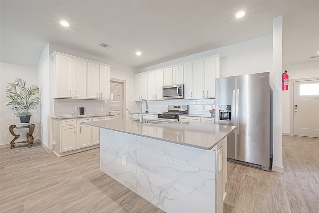 kitchen featuring white cabinets, light wood-type flooring, backsplash, and stainless steel appliances