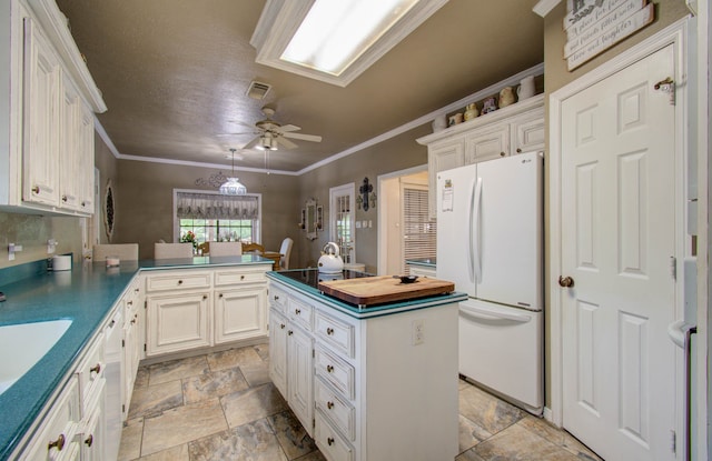 kitchen with white cabinets, kitchen peninsula, white fridge, crown molding, and ceiling fan