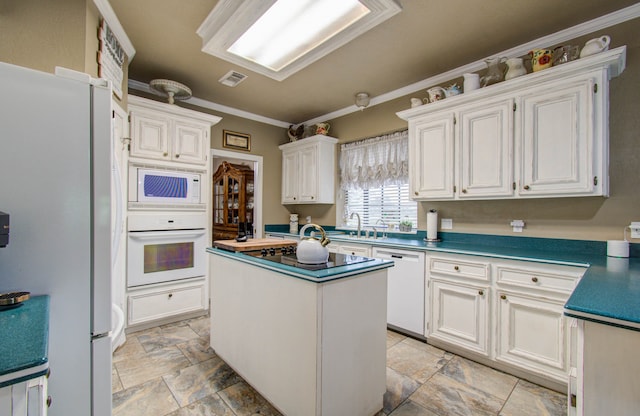 kitchen featuring ornamental molding, white appliances, a kitchen island, and white cabinets