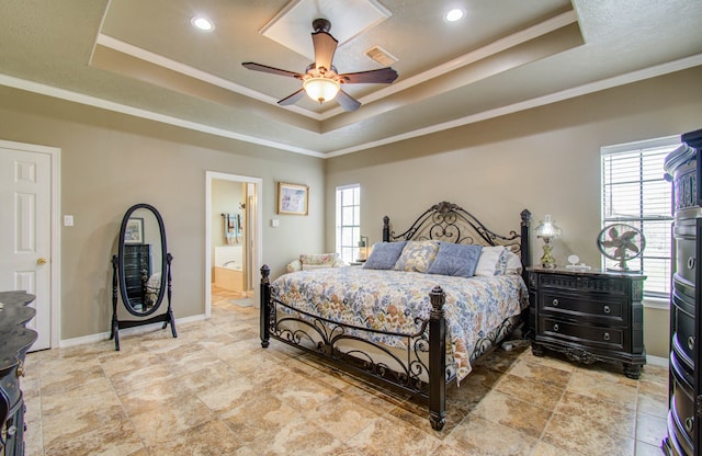 bedroom with ceiling fan, a raised ceiling, ensuite bath, and ornamental molding