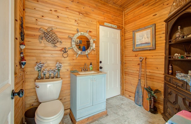 bathroom with wood walls, vanity, and toilet