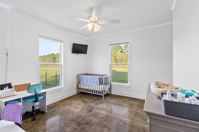 bedroom featuring multiple windows, ceiling fan, and a nursery area