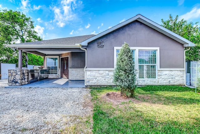 view of front of home with exterior bar, a front yard, an outdoor kitchen, and a patio area