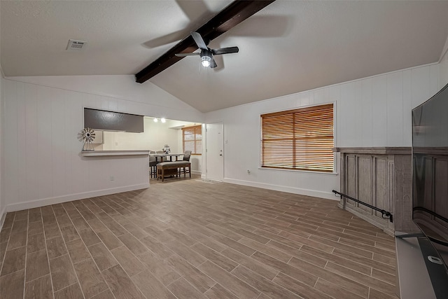 unfurnished living room featuring hardwood / wood-style floors, lofted ceiling with beams, a textured ceiling, and ceiling fan