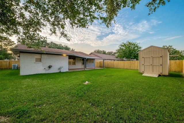 yard at dusk with a storage unit, a patio area, and central air condition unit