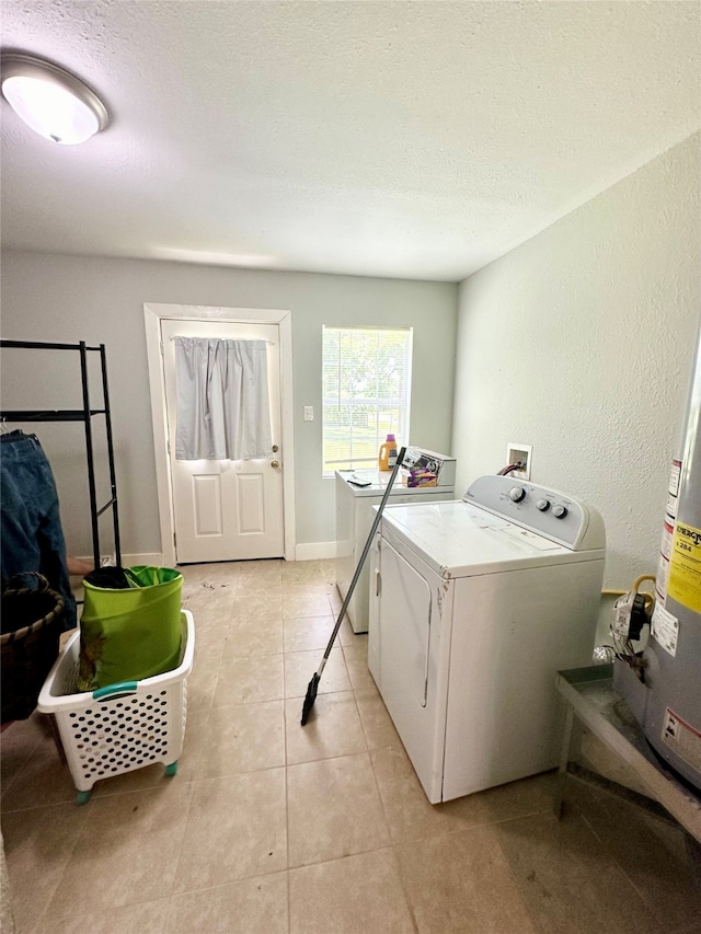 laundry area with light tile patterned floors, gas water heater, washing machine and clothes dryer, and a textured ceiling