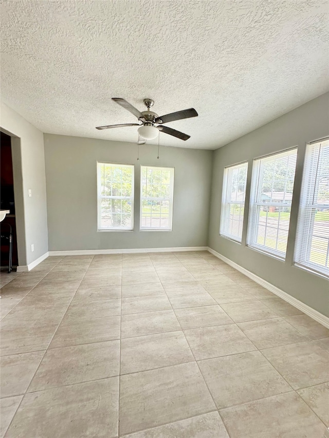 tiled spare room with a wealth of natural light, ceiling fan, and a textured ceiling