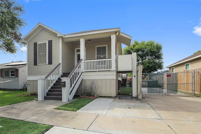 view of front facade featuring stairs, a gate, fence, and a porch