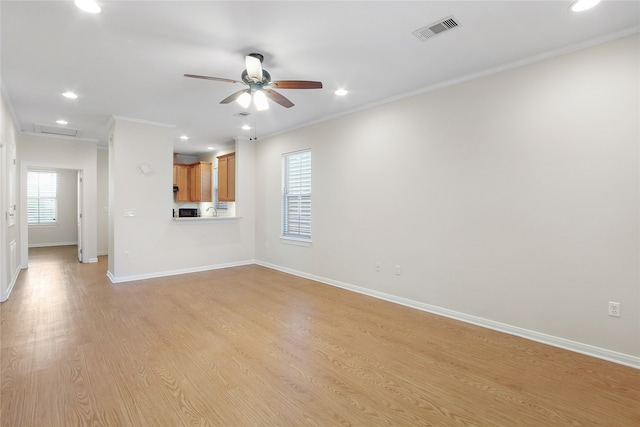 unfurnished living room with light wood-type flooring, crown molding, ceiling fan, and a healthy amount of sunlight