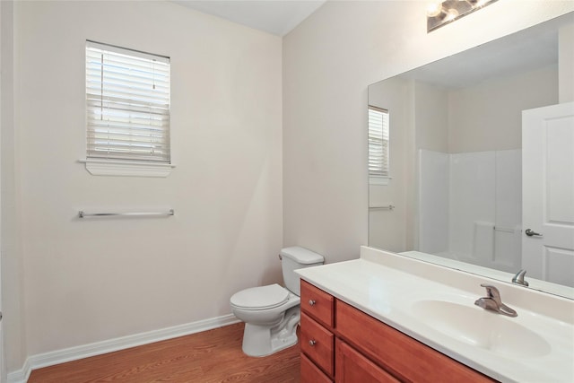 full bath with toilet, wood finished floors, vanity, baseboards, and walk in shower