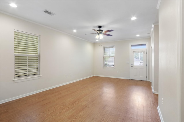 unfurnished room with light wood-style floors, visible vents, crown molding, and baseboards