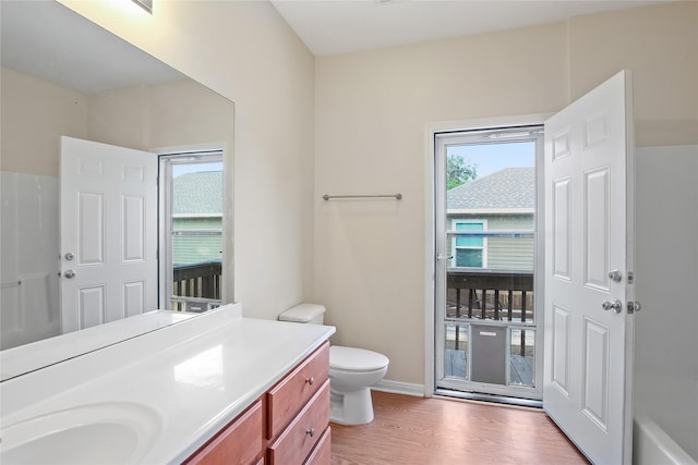 full bathroom featuring toilet, baseboards, wood finished floors, and vanity