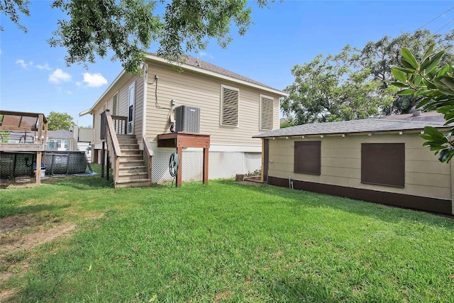 back of property with a wooden deck, stairs, central AC unit, and a yard