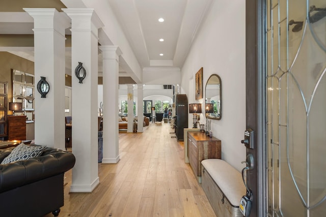 entryway featuring ornate columns, a high ceiling, light wood finished floors, and recessed lighting