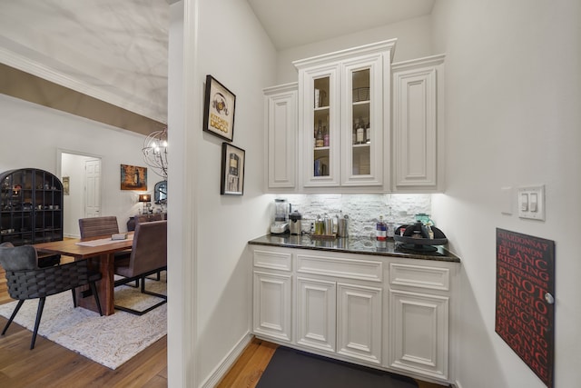 bar with hardwood / wood-style floors, a chandelier, tasteful backsplash, and white cabinets