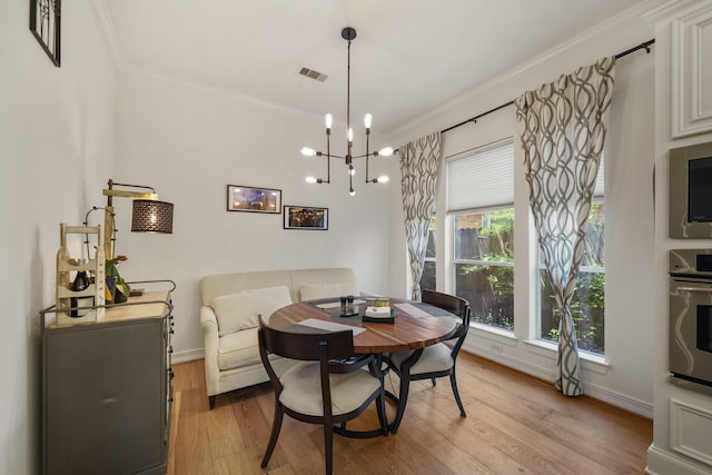 dining space featuring crown molding, light hardwood / wood-style flooring, and a chandelier