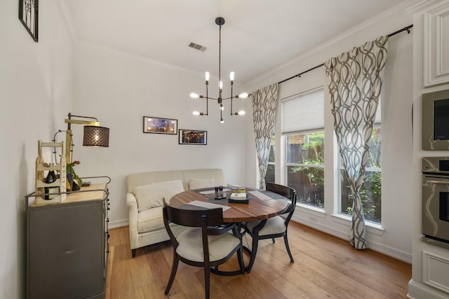 dining area featuring crown molding, visible vents, baseboards, light wood finished floors, and an inviting chandelier