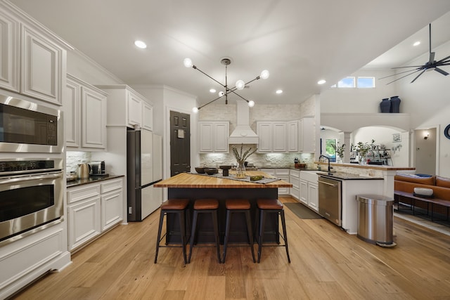 kitchen featuring custom exhaust hood, light wood-type flooring, a center island, and stainless steel appliances