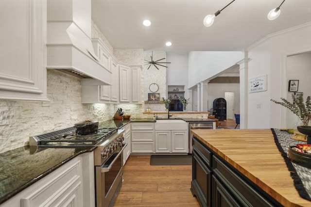 kitchen featuring stainless steel appliances, decorative columns, wooden counters, and white cabinets