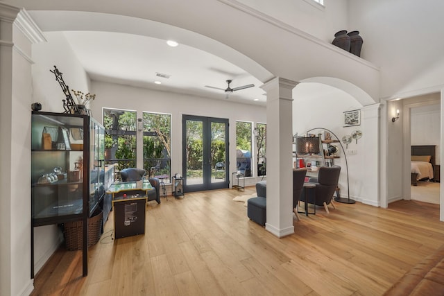 interior space with light wood-style floors, arched walkways, french doors, and decorative columns