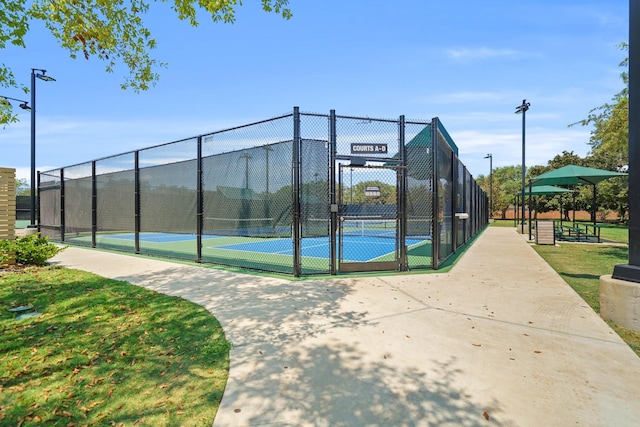 view of tennis court with a gate and fence