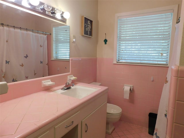 full bath with a wainscoted wall, tile walls, toilet, vanity, and tile patterned floors