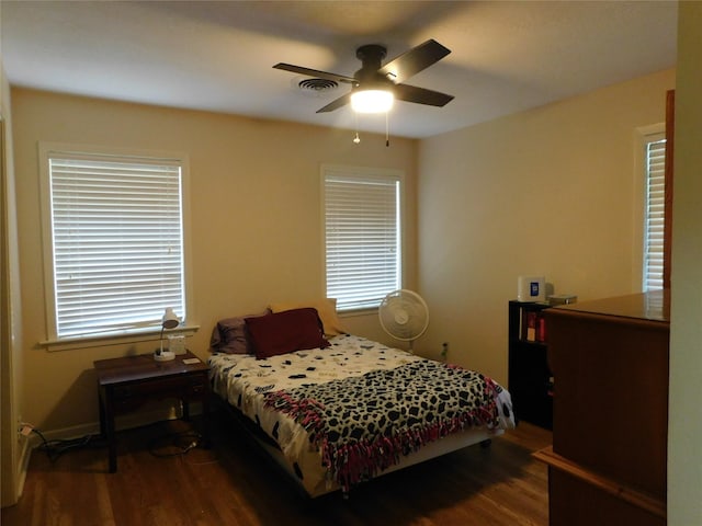 bedroom featuring multiple windows, wood finished floors, visible vents, and a ceiling fan