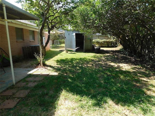 view of yard featuring an outbuilding, a patio area, fence, and a shed