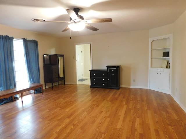 interior space featuring baseboards, visible vents, ceiling fan, and light wood finished floors