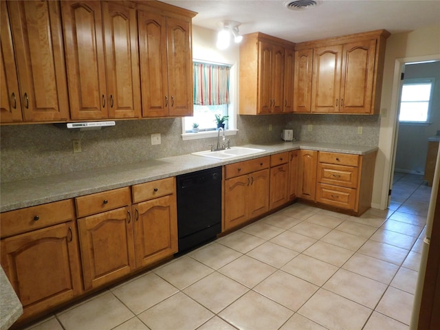 kitchen featuring plenty of natural light, tasteful backsplash, brown cabinetry, dishwasher, and a sink