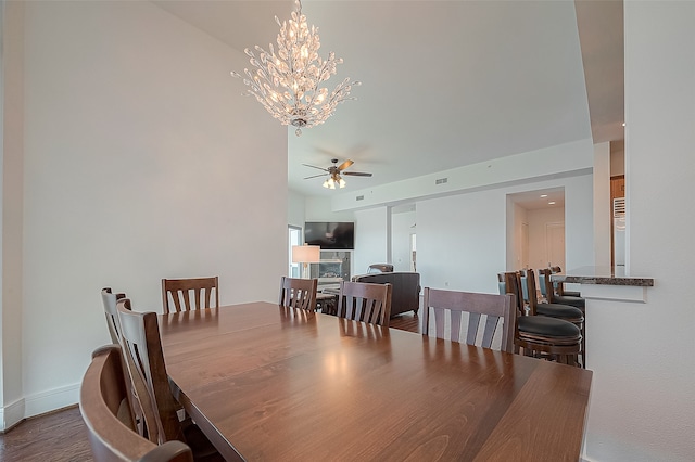 dining space featuring ceiling fan with notable chandelier and hardwood / wood-style flooring