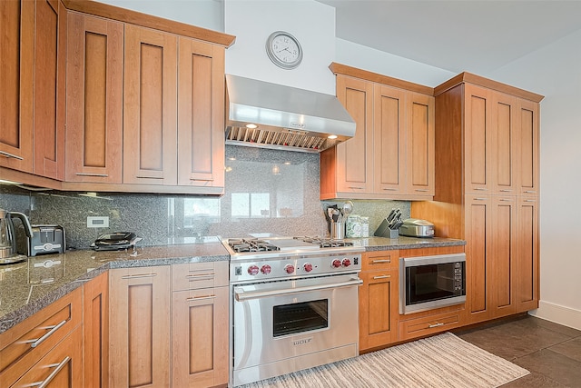 kitchen featuring decorative backsplash, black microwave, wall chimney exhaust hood, dark tile patterned flooring, and luxury range