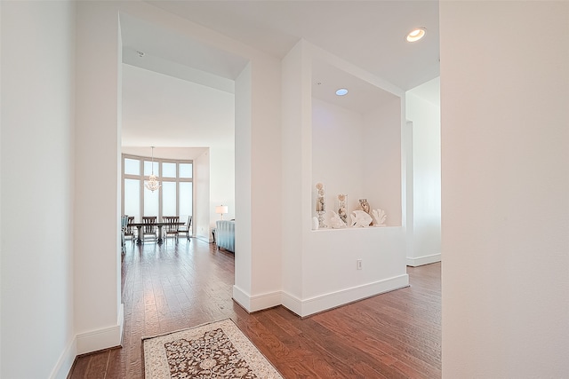 hall featuring hardwood / wood-style flooring and an inviting chandelier