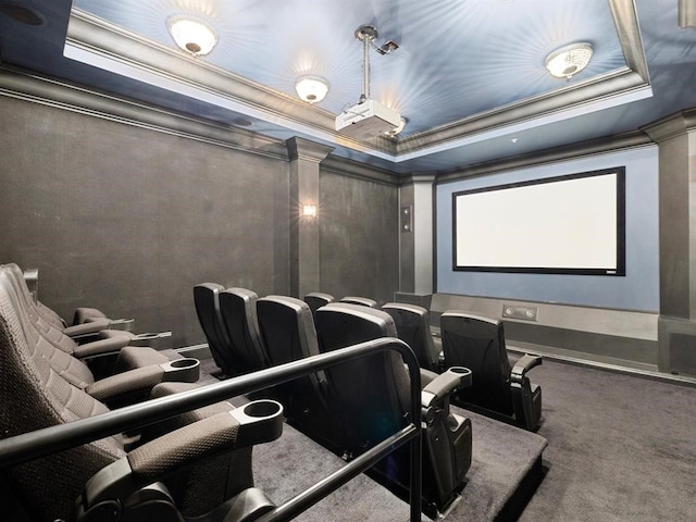 cinema room featuring ornate columns, a raised ceiling, carpet floors, and ornamental molding