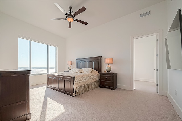 bedroom with ceiling fan, a water view, and light carpet