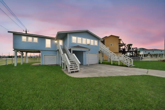 back house at dusk featuring a yard, a garage, and a carport