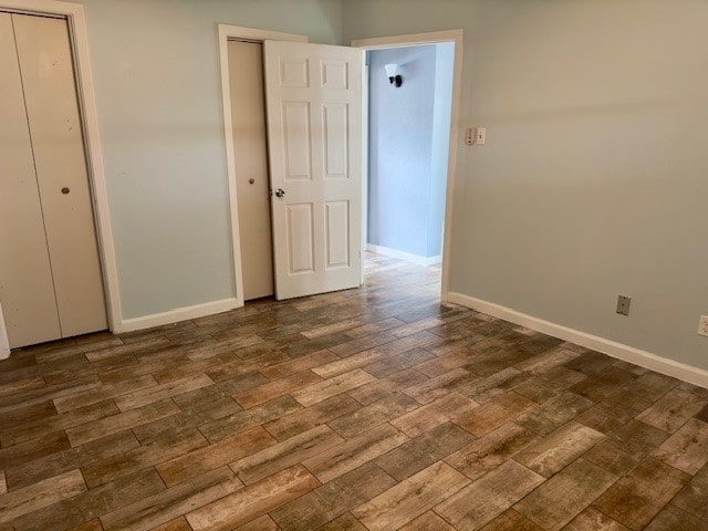 unfurnished bedroom with two closets and dark hardwood / wood-style flooring