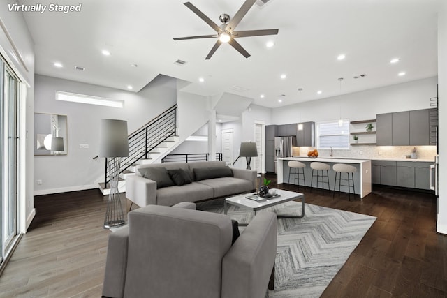 living room featuring hardwood / wood-style flooring, sink, and ceiling fan