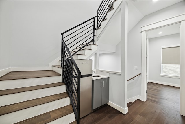 stairway with vaulted ceiling and hardwood / wood-style floors